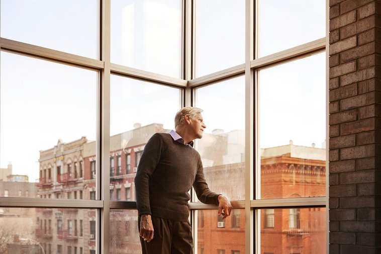 Man looking away while standing by window at home
