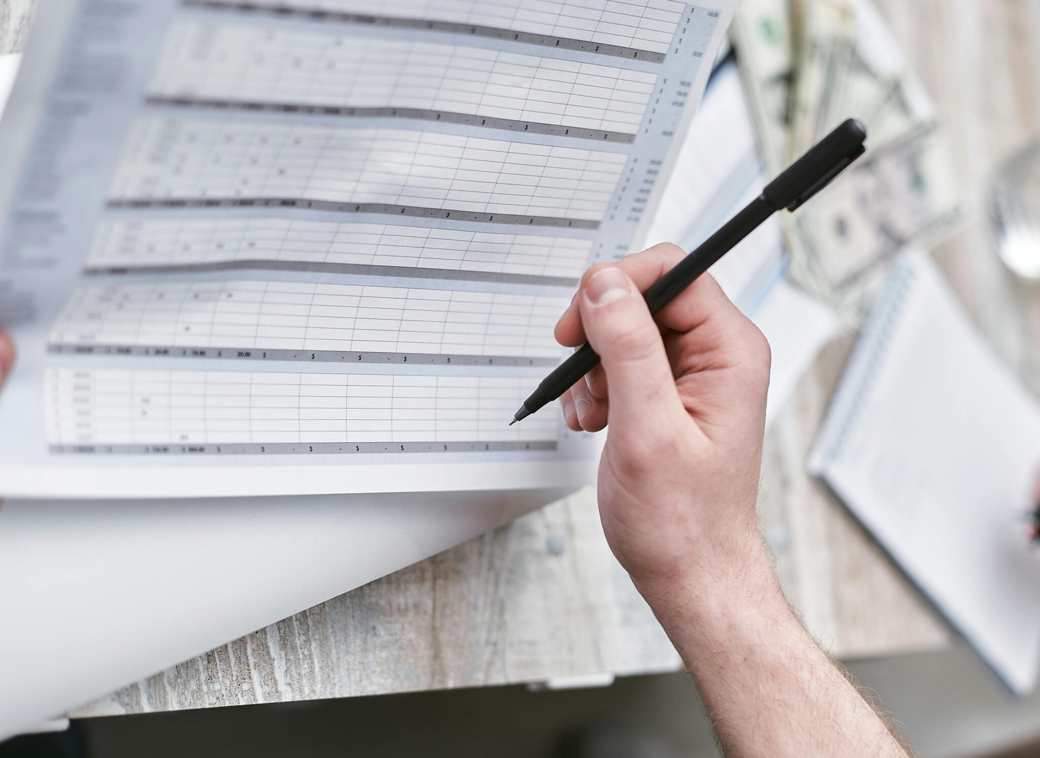 A photograph of a person holding a pen and reviewing the financials of a specific job.