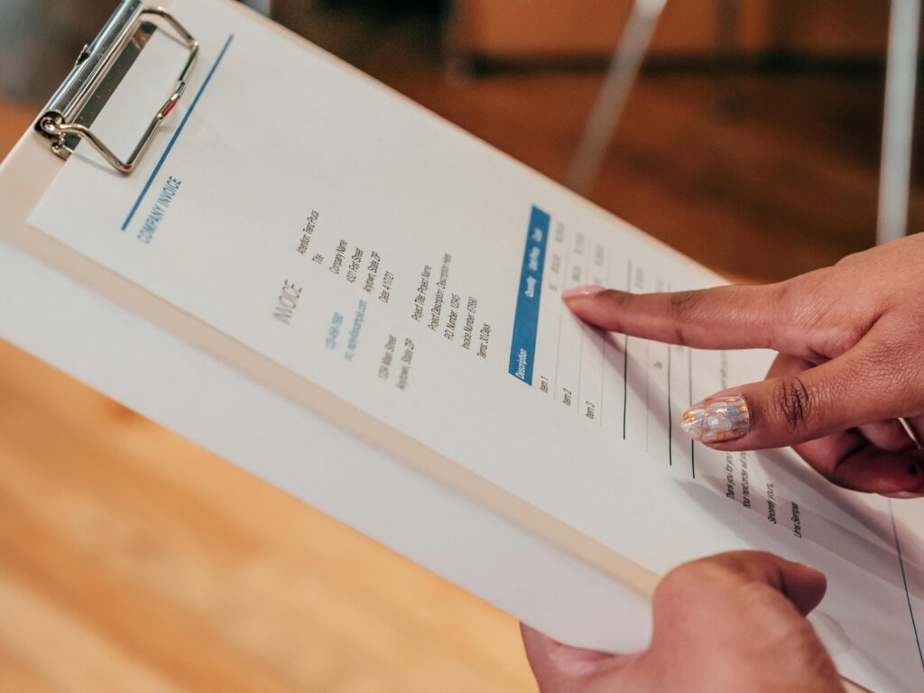 Construction professional reviewing a project invoice highlighting a retainage line item on a clipboard.