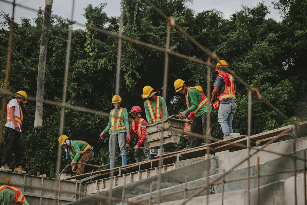 A group of construction workers in safety gear working on the foundation of a structure.