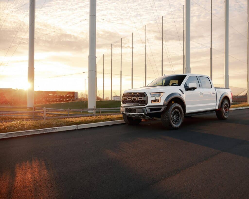 Pickup truck driving down the road at sunset