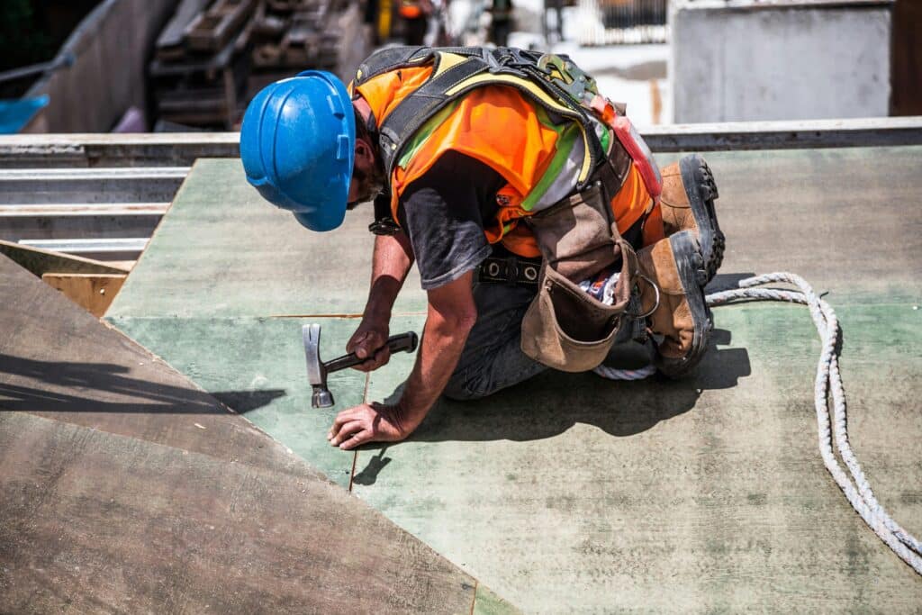 Construction contractor using a hammer on the roof of a building