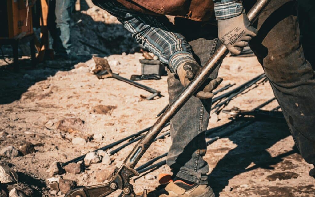 Construction contractor working on site, bending down with a tool in his hand
