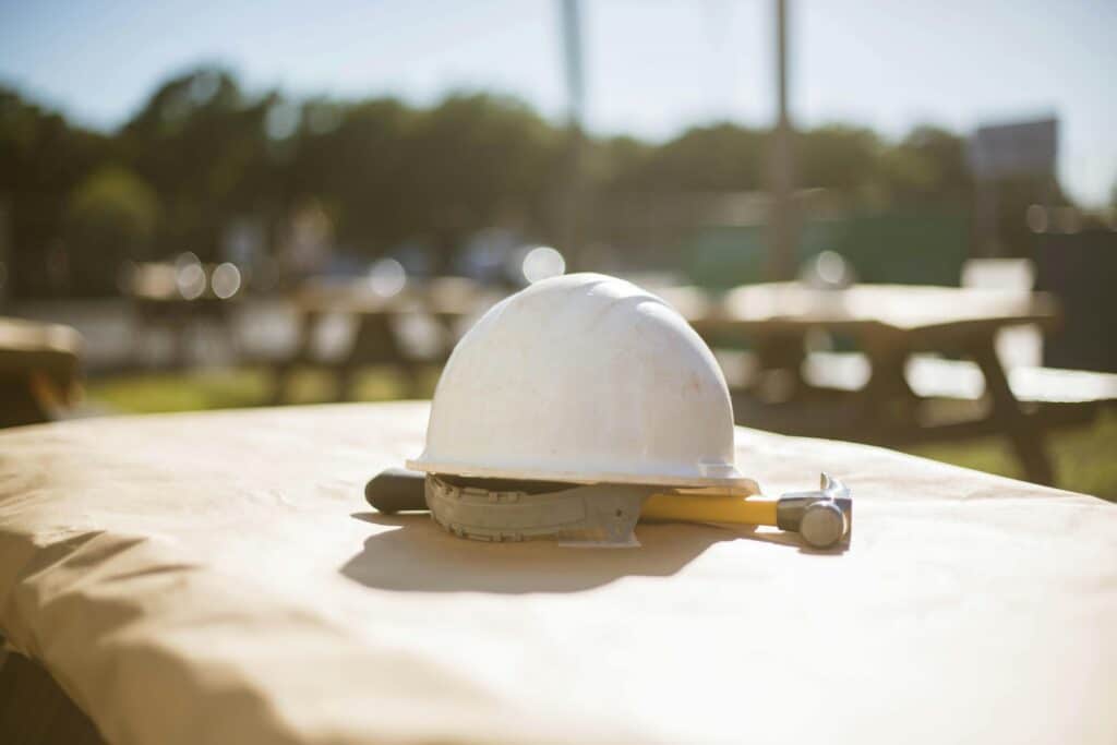 White hard hat sitting on a hammer sitting on a table outside