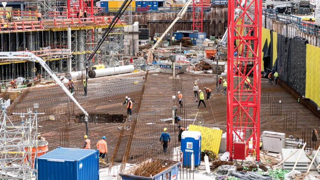 A construction site with several contractors walking and working on separate things.