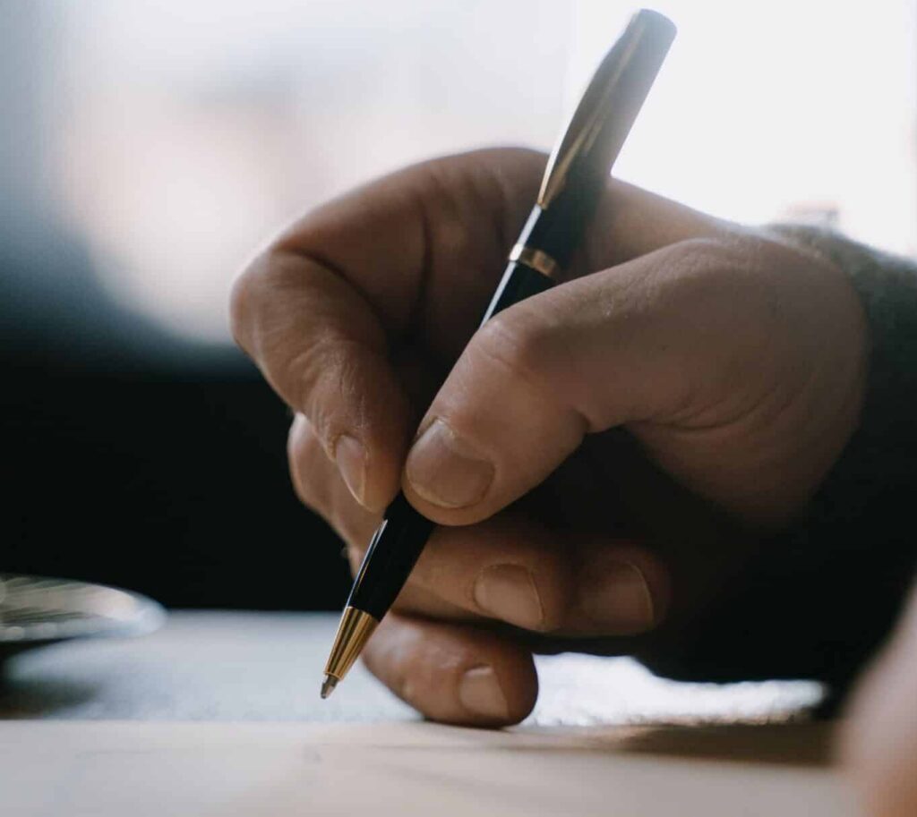A close up view of a hand signing a paper document