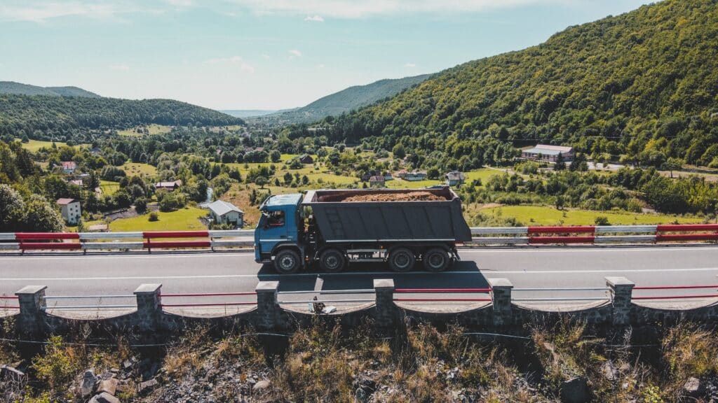 Dump truck driving down country side highway.